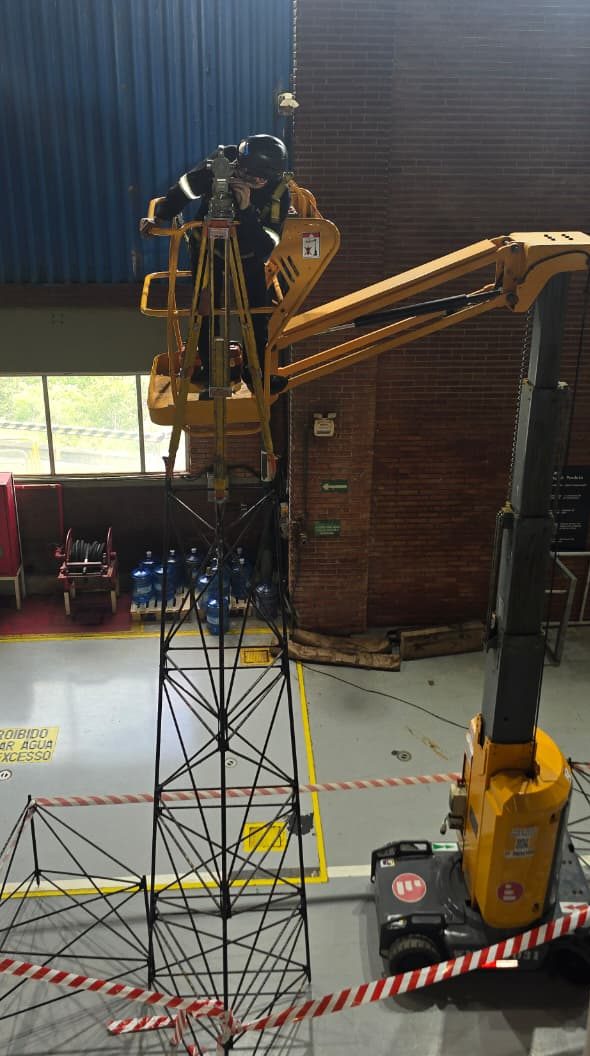 Equipe técnica realizando levantamento topográfico e alinhamento óptico em ambiente industrial
